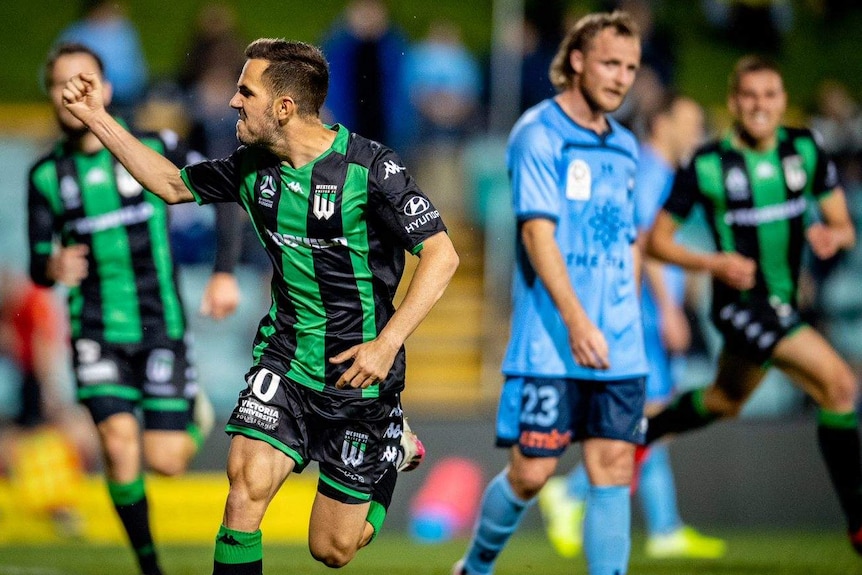An A-League player gestures with a clenched fist in celebration after scoring the winning goal.