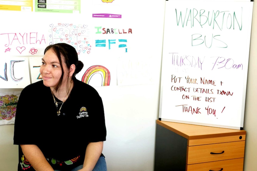 A woman sitting inside a room smiling.