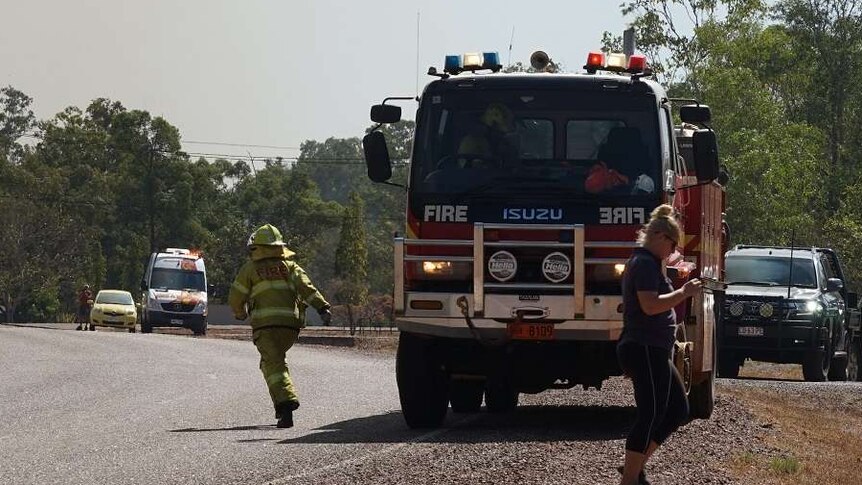 A firefighter runs away from a fire truck on a road outside of Darwin.