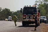A firefighter runs away from a fire truck on a road outside of Darwin.