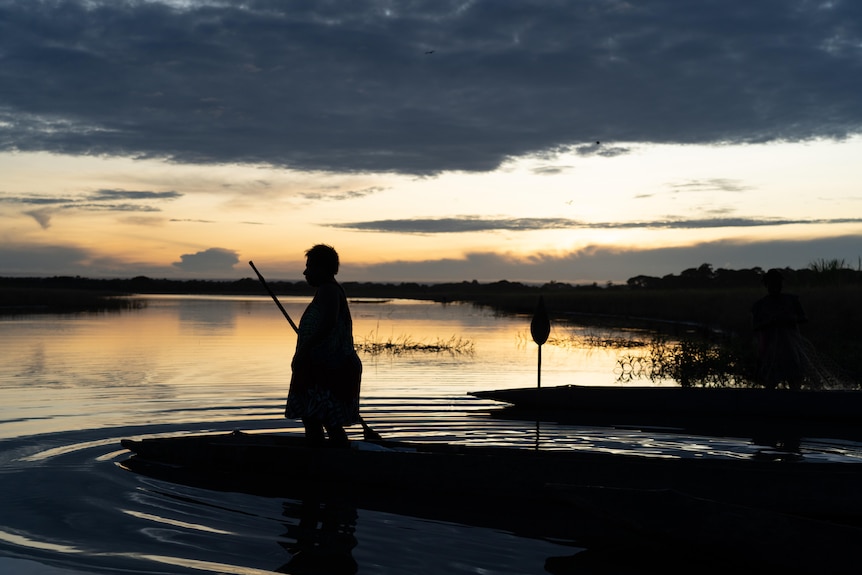 A woman on a canoe at sunrise.