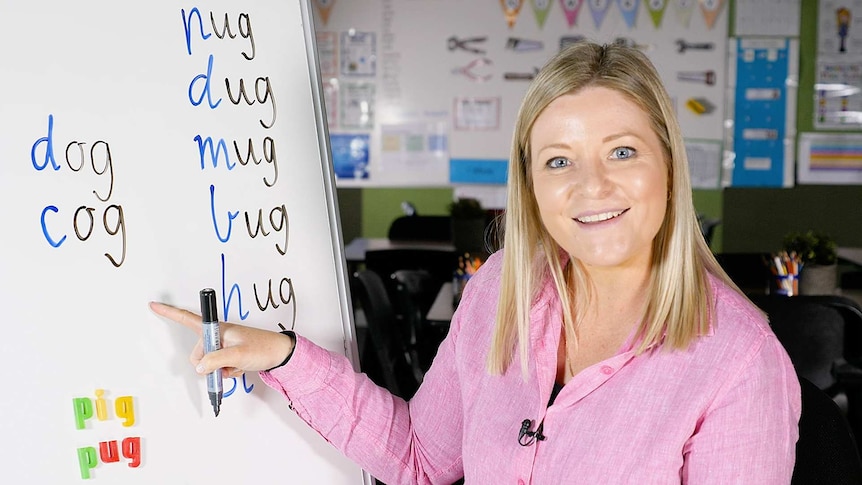 Female teacher points to words on whiteboard