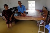 A couple watches TV in their flooded house.