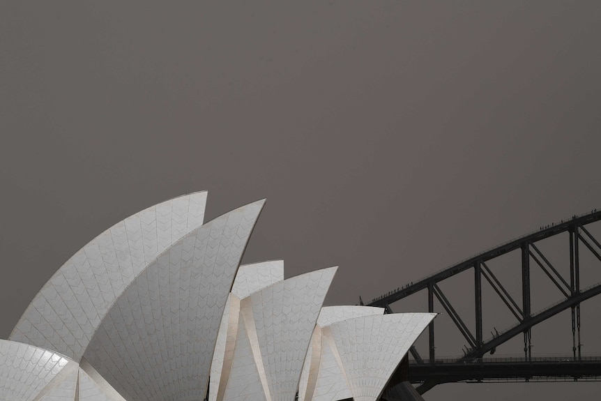 The Sydney Opera House stands in the left hand corner shrouded in dust with ominous brown/grey sky as storm plagues city.
