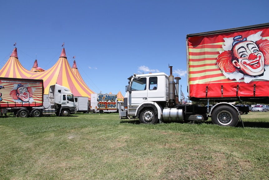 Circus trucks in front of a circus tent.