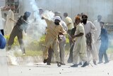 A Pakistani demonstrator throws a tear gas shell towards riot police