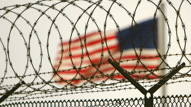 American flag waves within the razor wire-lined compound of Camp Delta.