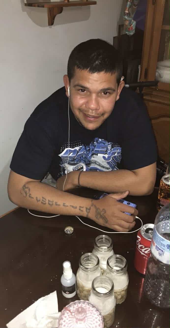 Um homem com um fone de ouvido conectado a um telefone se inclina para a frente com os braços apoiados sobre uma mesa.