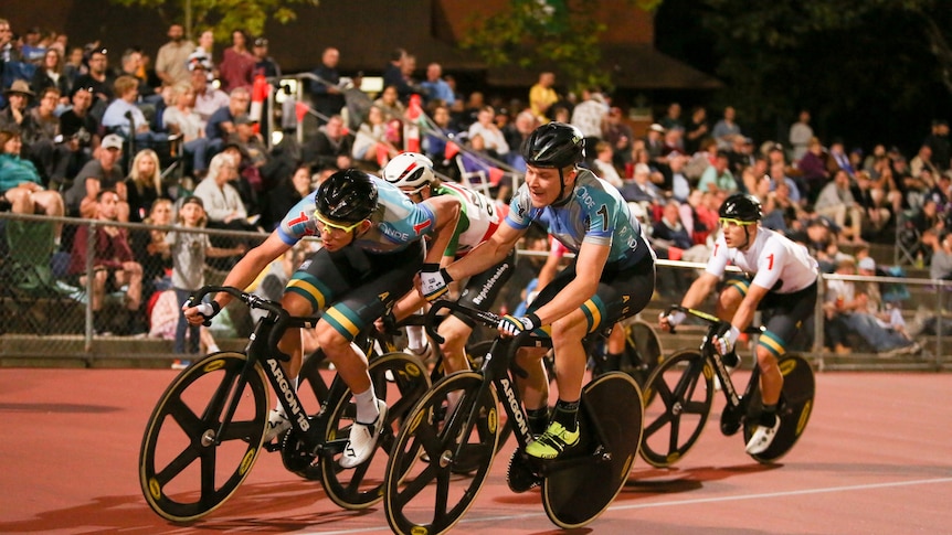 a photo of a pack of cyclists on an outside track 