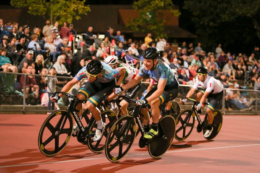 a photo of a pack of cyclists on an outside track 