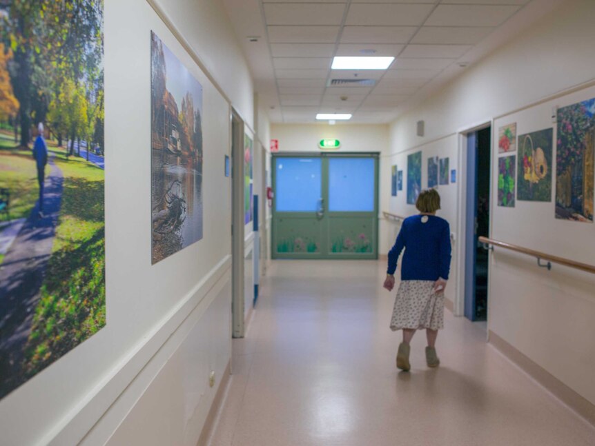 Dorothy walks down the hospital corridor, decorated with landscape photography.