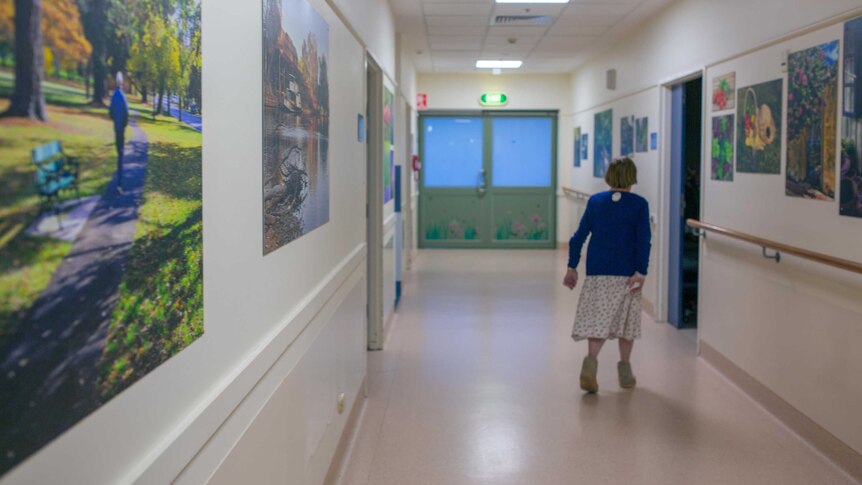 Dorothy walks down the hospital corridor, decorated with landscape photography.