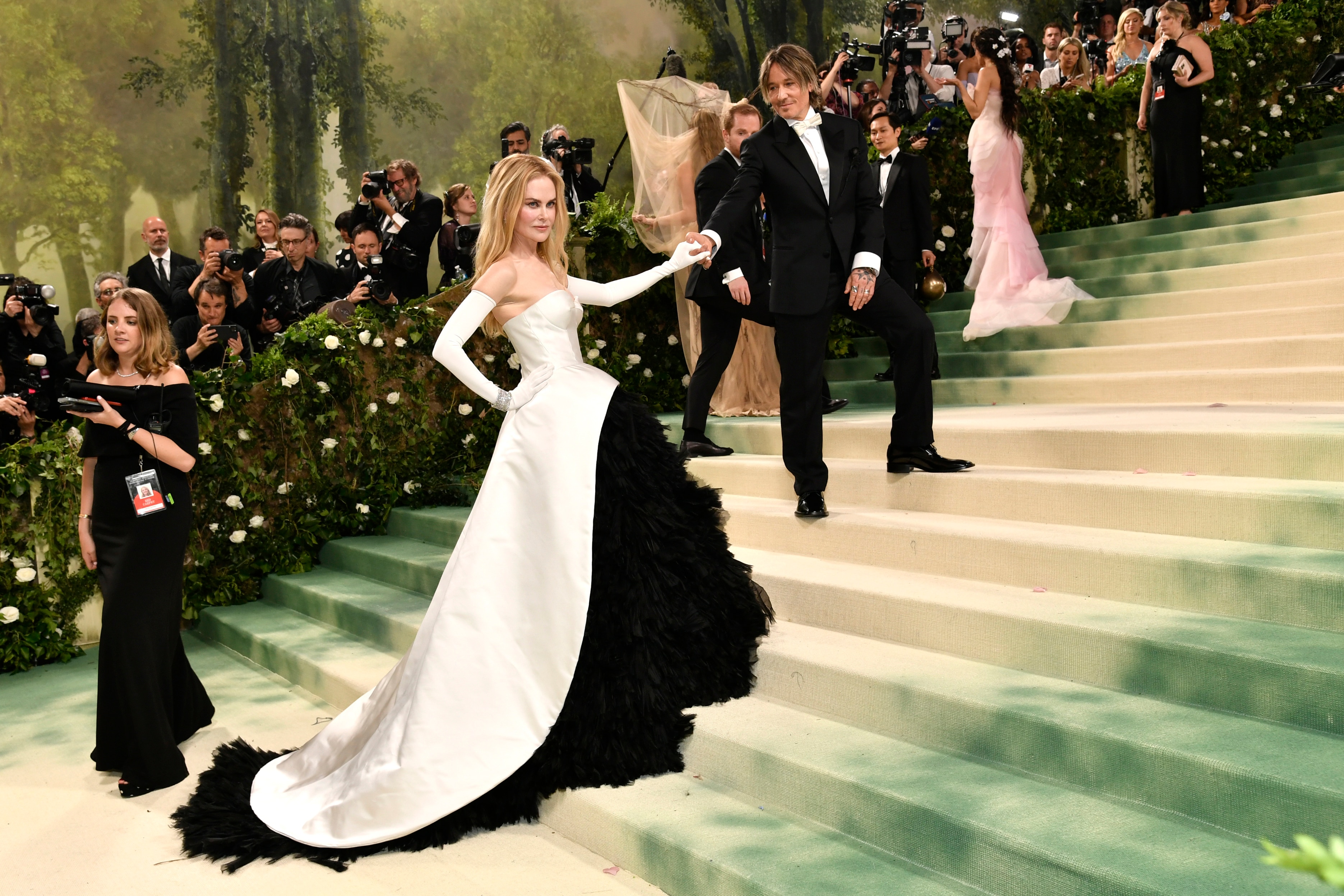 Nicole Kidman wearing a long silky white gown with black ruffly skirt and white sleeves. Keith Urban wears a black suit.