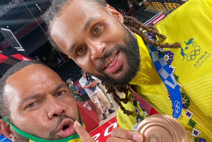 Junior Viranatuleo and point guard Patty Mills holding a bronze Olympic medal 
