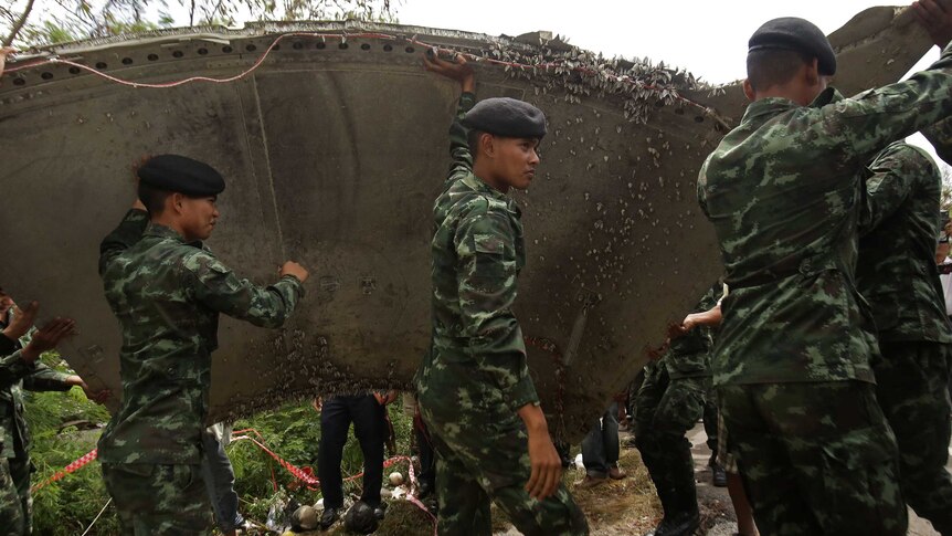 Thai soldiers carry a piece of suspected aircraft debris