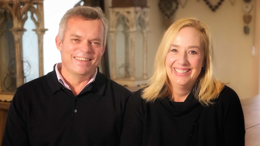 A man and woman sit side by side smiling