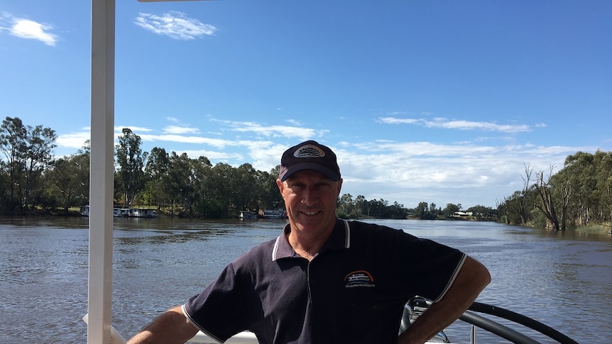 Man standing on houseboat with Murray River in the background.