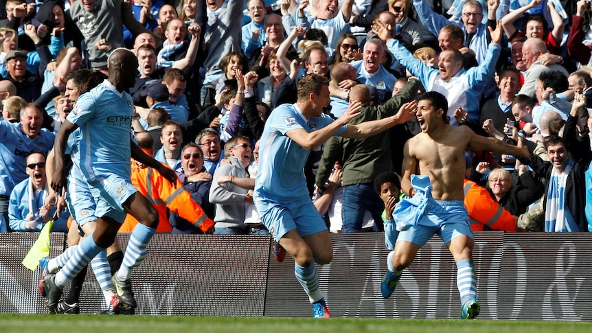 A shirtless Premier League footballer screams in joy as his teammates and fans rejoice.