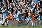 A shirtless Premier League footballer screams in joy as his teammates and fans rejoice.
