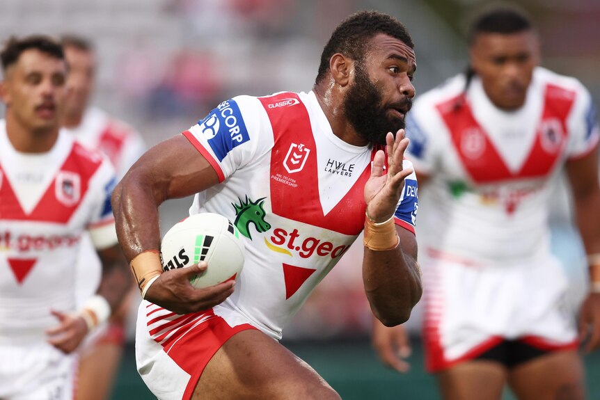 A St George Illawarra NRL player runs with the ball in his right hand.