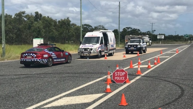 Police cars parked on the side of the road with witch's hats and a stop sign