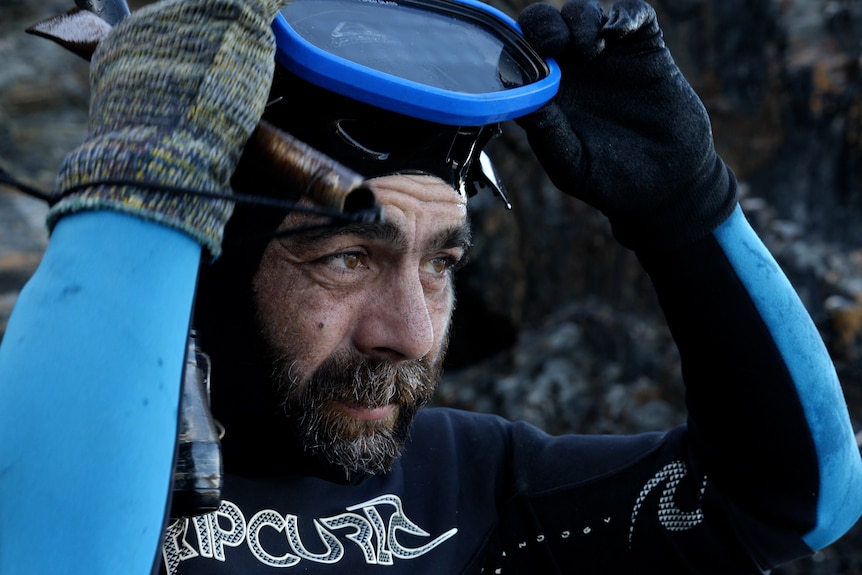 A close up photo of an indigenous man in a diving outfit and goggles 