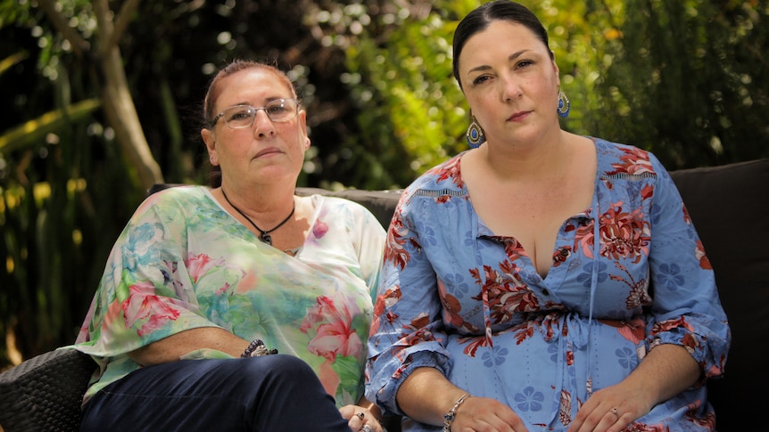 A mother and daughter sitting side by side. Both are wearing floral prints.