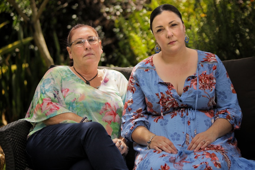 A mother and daughter sitting side by side. Both are wearing floral prints.