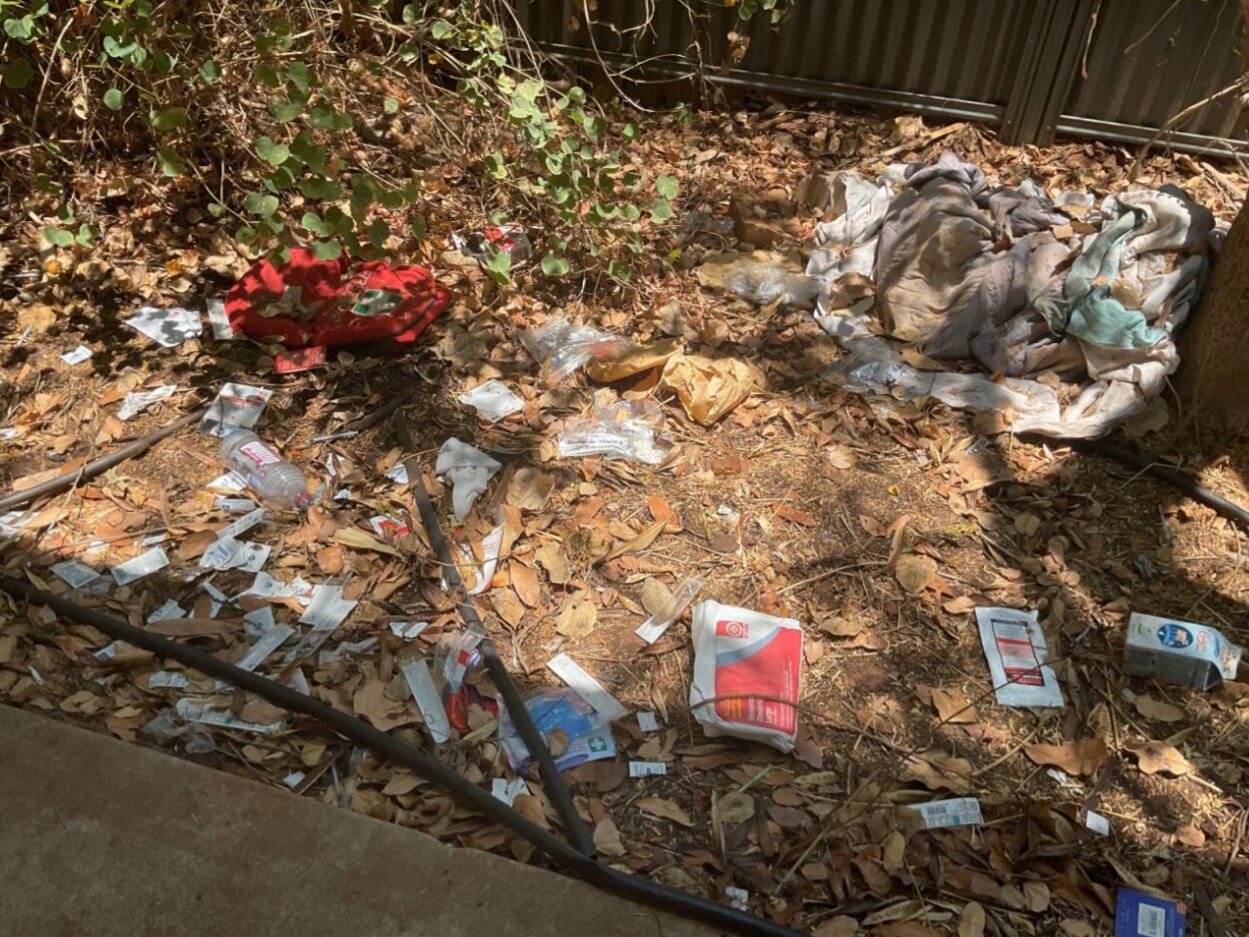 Lixo e papel em cima de sujeira e folhas.