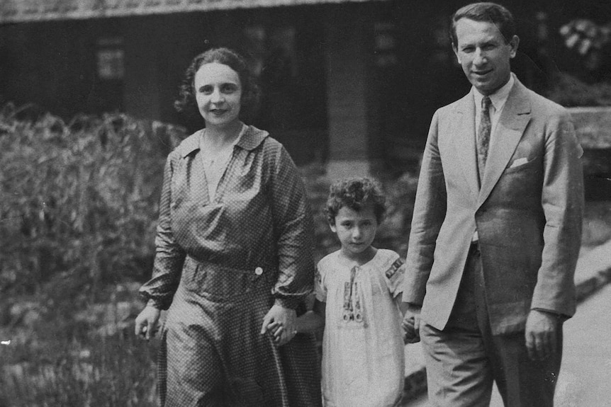 A young Beate Sirota holds her parents' hands.