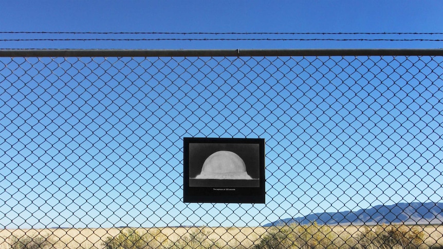 Mushroom cloud photograph on fence in front of White Sands Missile Range in New Mexico