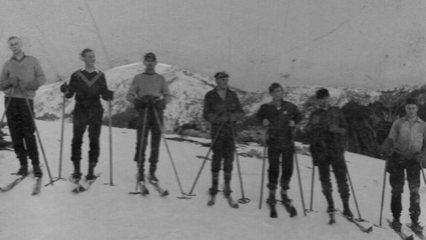 a black and white photo of seven skiers.