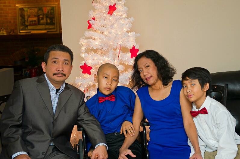 Haris Simangunsong sits with his wife and two children in front of a Christmas tree.