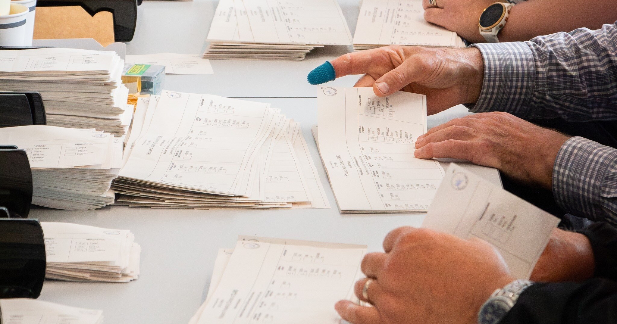 Close-up of the hands of election workers counting votes