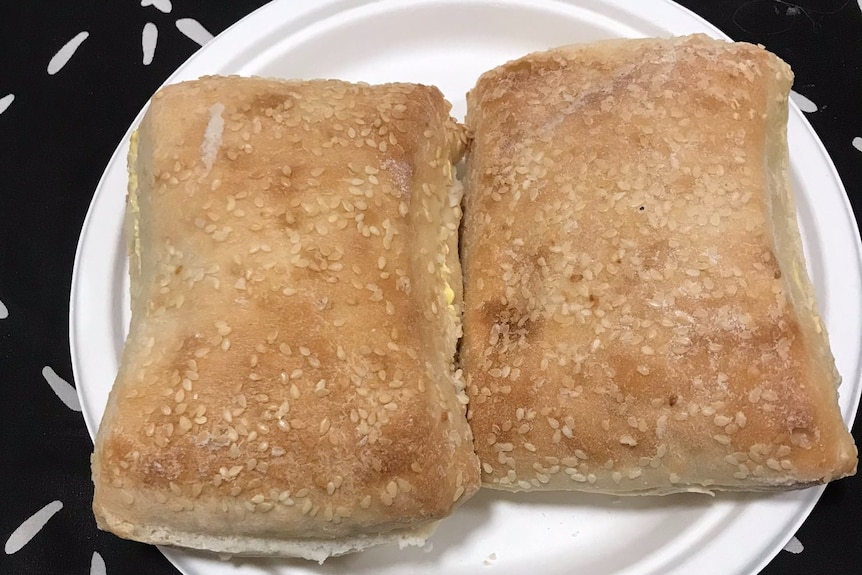 Two bread rolls sit on a white plate