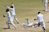 Sri Lanka cricket teammates celebrating on the field while Australia batsman Peter Nevill lies on the ground in defeat.