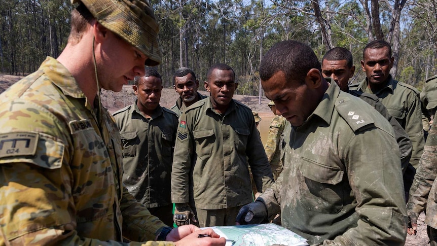 An Australian soldier points to a map alongside a Fijian soldier.