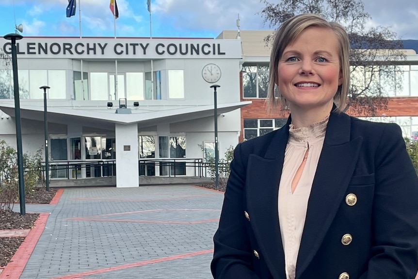 A woman wearing a dark blazer standing in front of the Glenorchy City Council building.