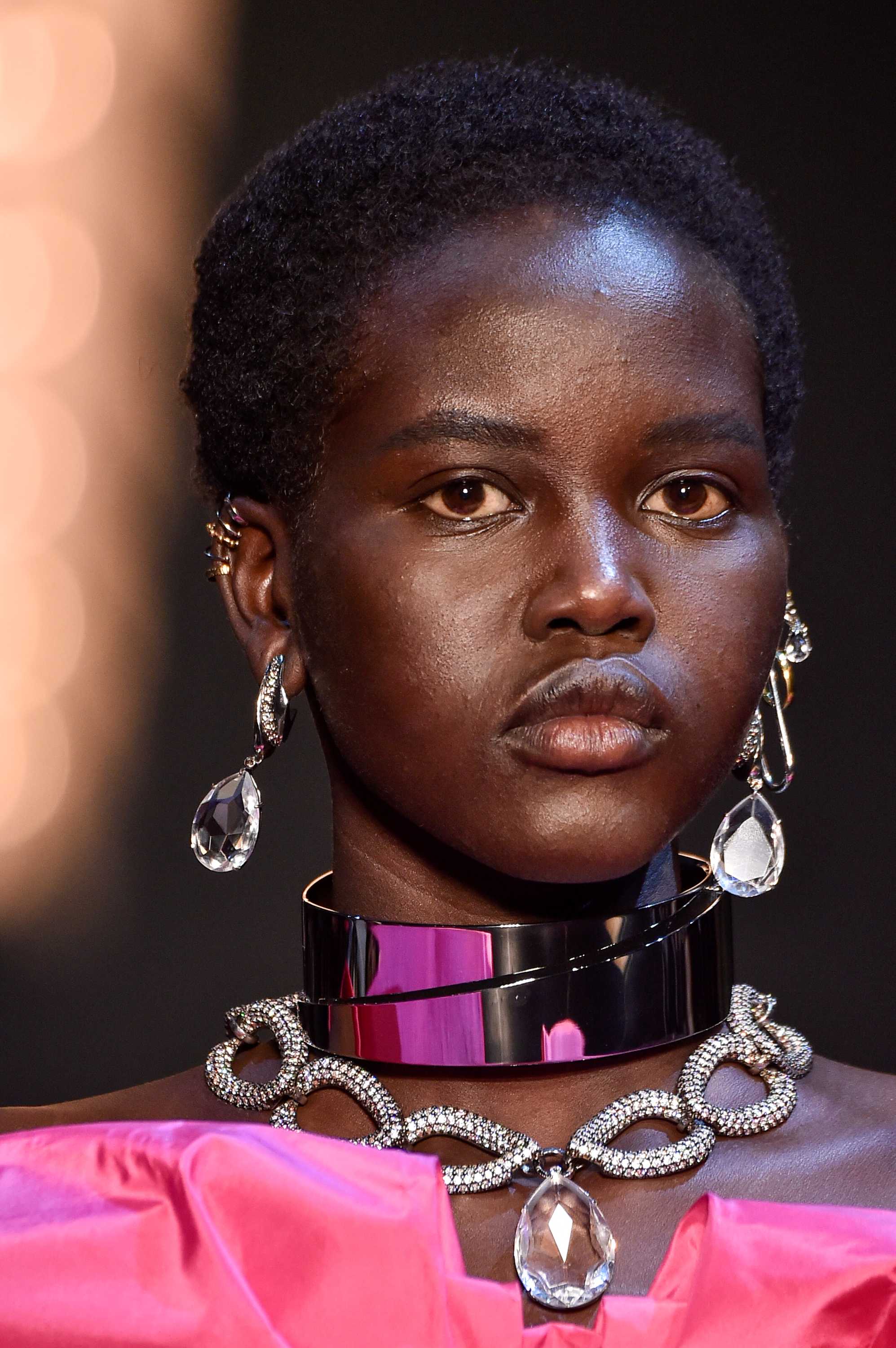 A midshot of a model with short hair, silver necklace and large silver earrings.