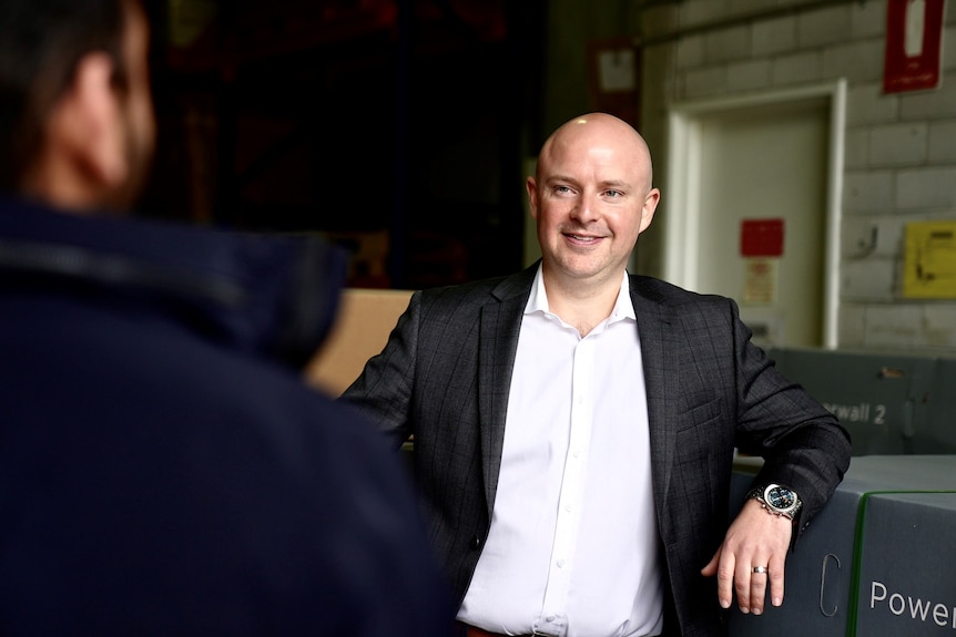 a man in a suit smiling in a warehouse