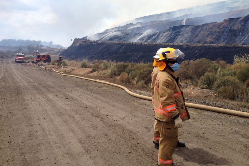 Two firefighters stand on the road below the burning coal face in Hazelwood mine on March 5, 2014.