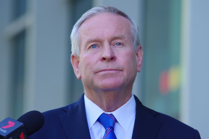 A man with grey hair and piercing eyes – former WA premier Colin Barnett – at a news conference.