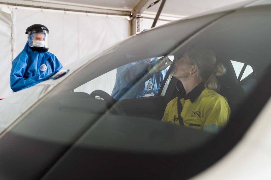 A Mineral Resources worker is nasally swabbed for COVID-19 in her car in Perth.