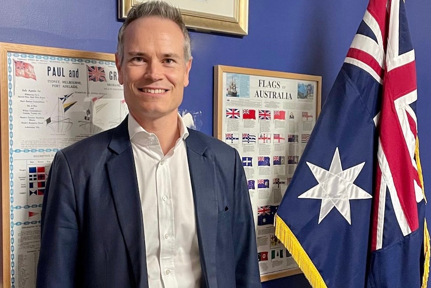 a man standing next to the australian flag