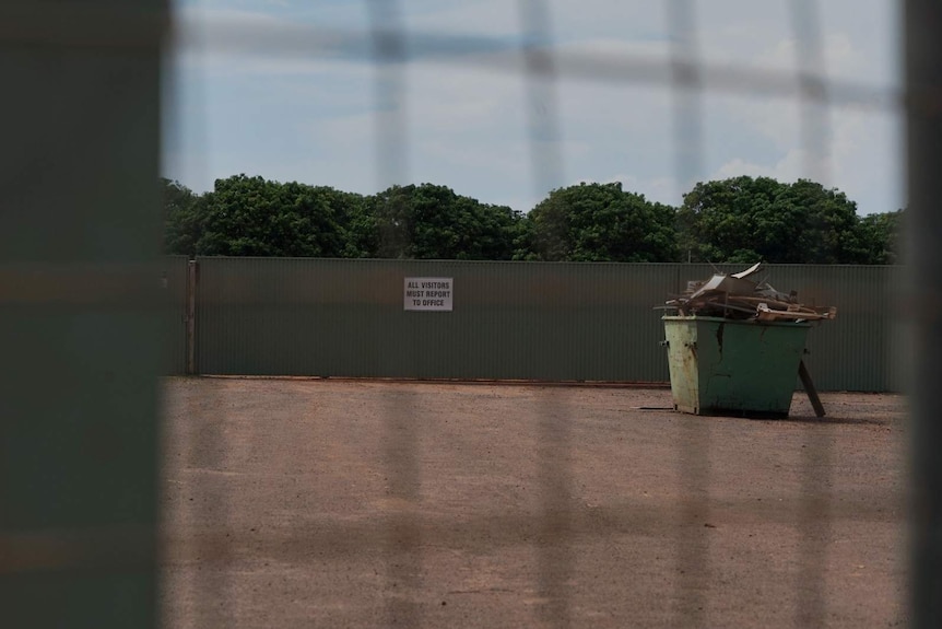 A fenced off yard at 35 Stevens Road, with a sign reading 'all visitors must report to office' visible.