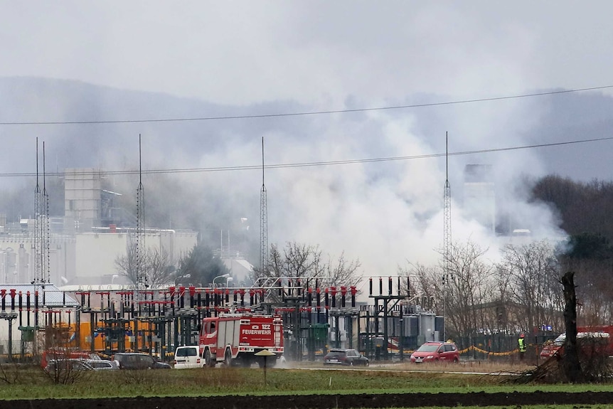 Firetrucks arrive at the scene of an explosion, shrouded in steam.