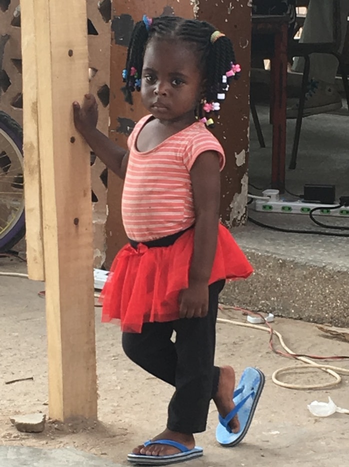 A young girl of African appearance looks sad while wearing a red dress.