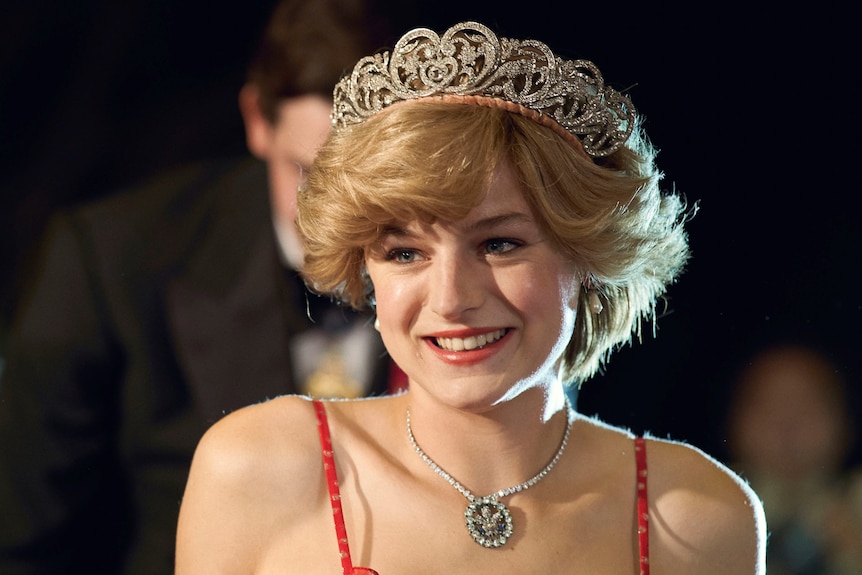 Actor Emma Corrin as Princess Diana, red spotty dress and blonde hair adorned with a small crown