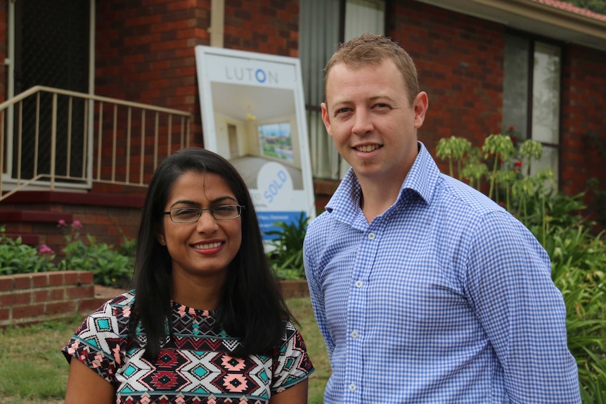 A couple in front of their new house.