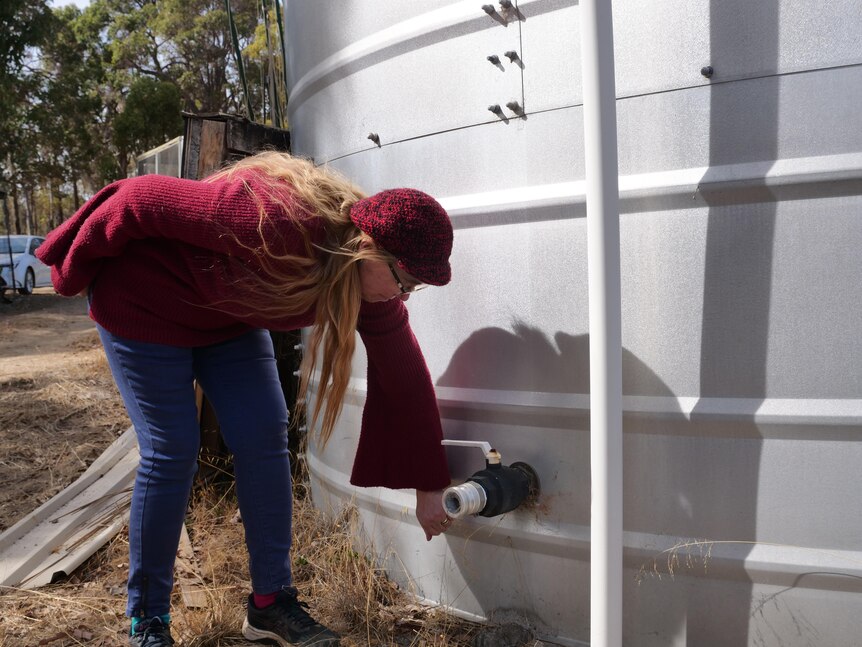 Estelle Rowcliffe, who lives near Bridgetown, checks the valve on her rainwater tank on her rural property.